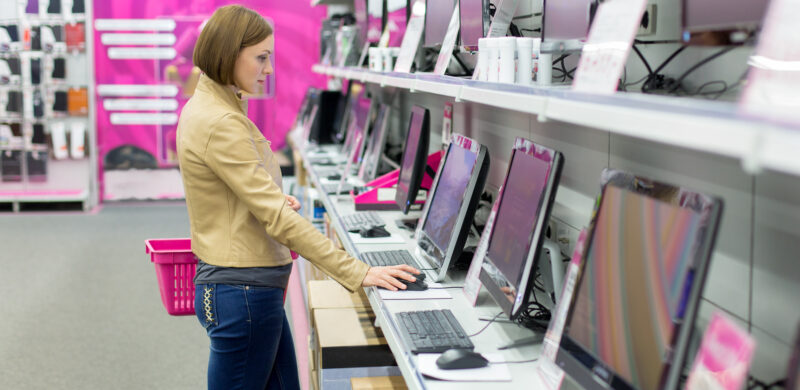Eine Damen interessiert sich in einem Einzelhandelsgeschäft für den Kauf eines Desktop-PCs.