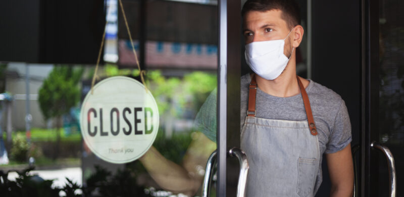 Imagefoto: Mann mit Maske steht vor einem geschlossenen Laden