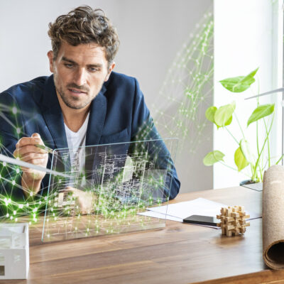 Foto eines Mannes, der mit Hilfe digitaler Virtual-Reality-Techniken futuristisch einen Laptop skizziert.
