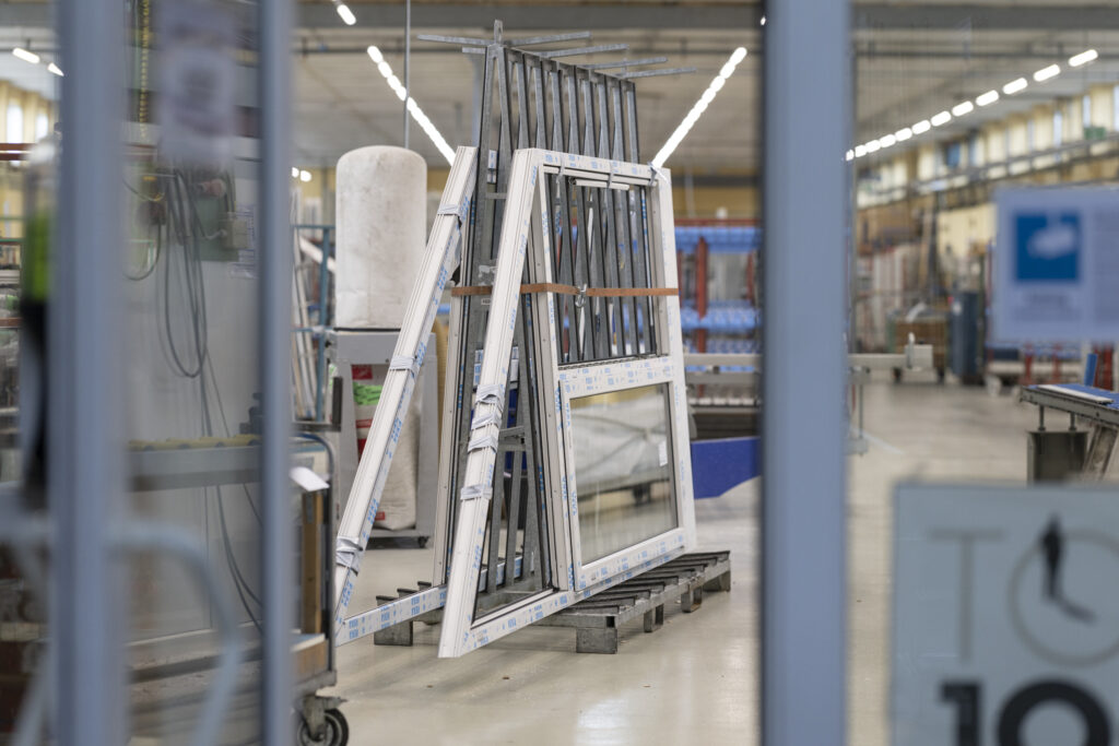 Einblicke in eine Produktionshalle: Ein großes, gefertigtes Fenster ist im Vordergrund gut sichtbar.